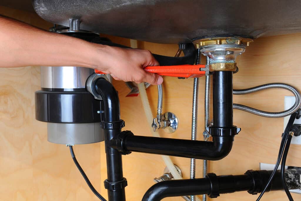 Installing a garbage disposal unit under the kitchen sink for efficient waste management.