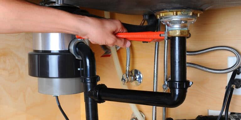 Installing a garbage disposal unit under the kitchen sink for efficient waste management.