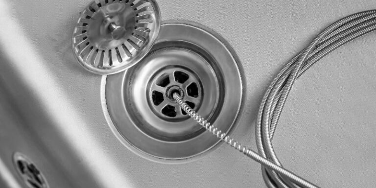 Close-up of a plumber cleaning a drain using a plumber snake tool