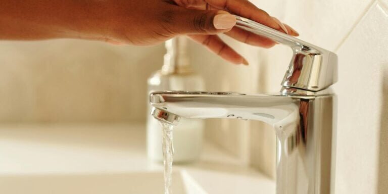 Chrome faucet with water flowing in a modern bathroom