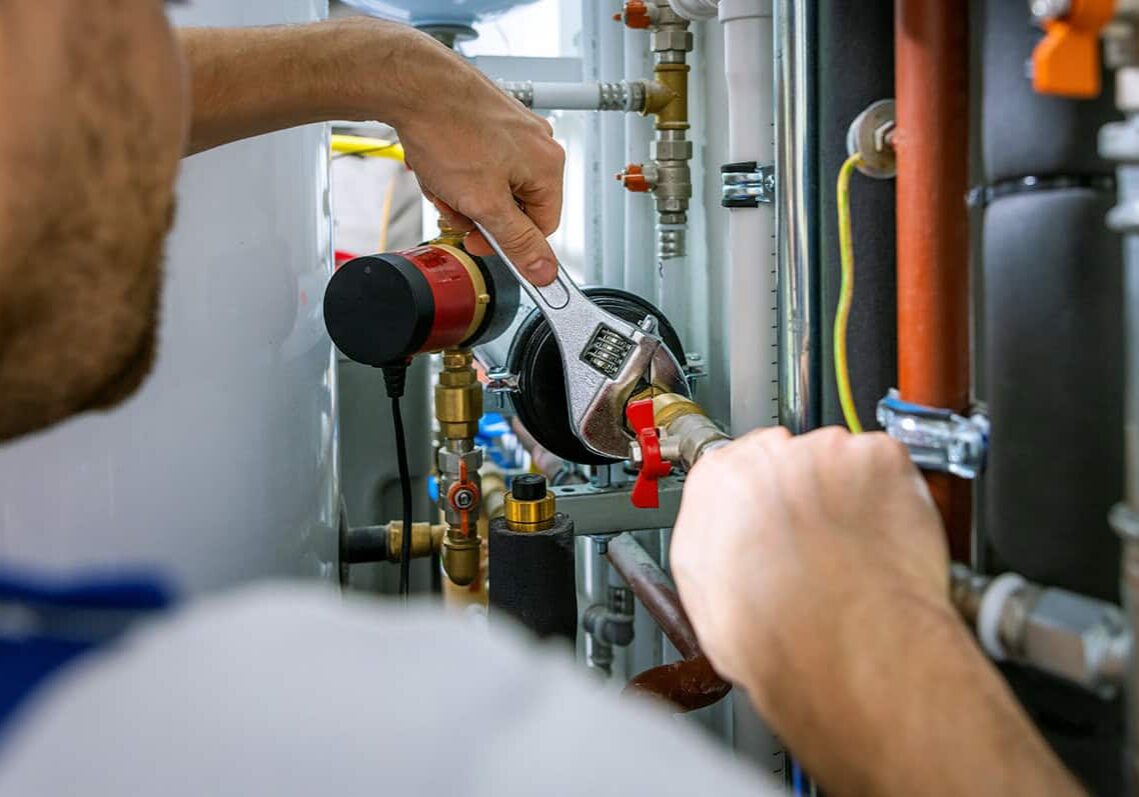 Professional plumber fixing pipes with wrench in residential plumbing system.