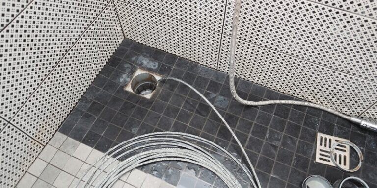 Plumber using a drain snake cable to clean and unclog a sewer line